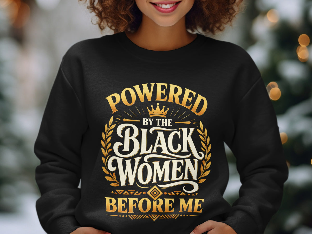 Black sweatshirt with "Powered by the Black Women Before Me" text in gold.