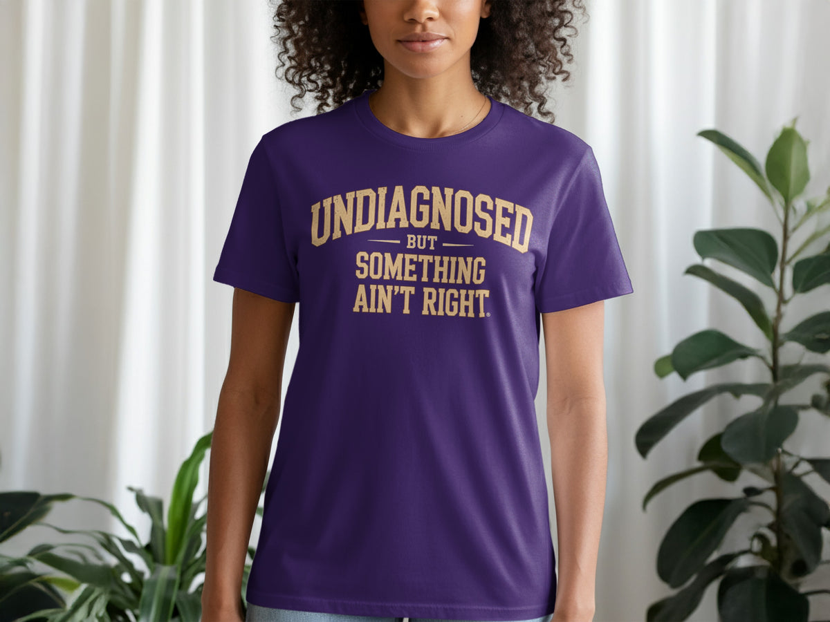 Purple t-shirt with gold text: "UNDIAGNOSED BUT SOMETHING AIN'T RIGHT."