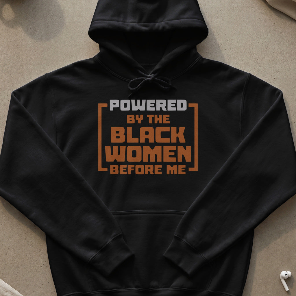 Black hoodie with "POWERED BY THE BLACK WOMEN BEFORE ME" text in orange and grey.