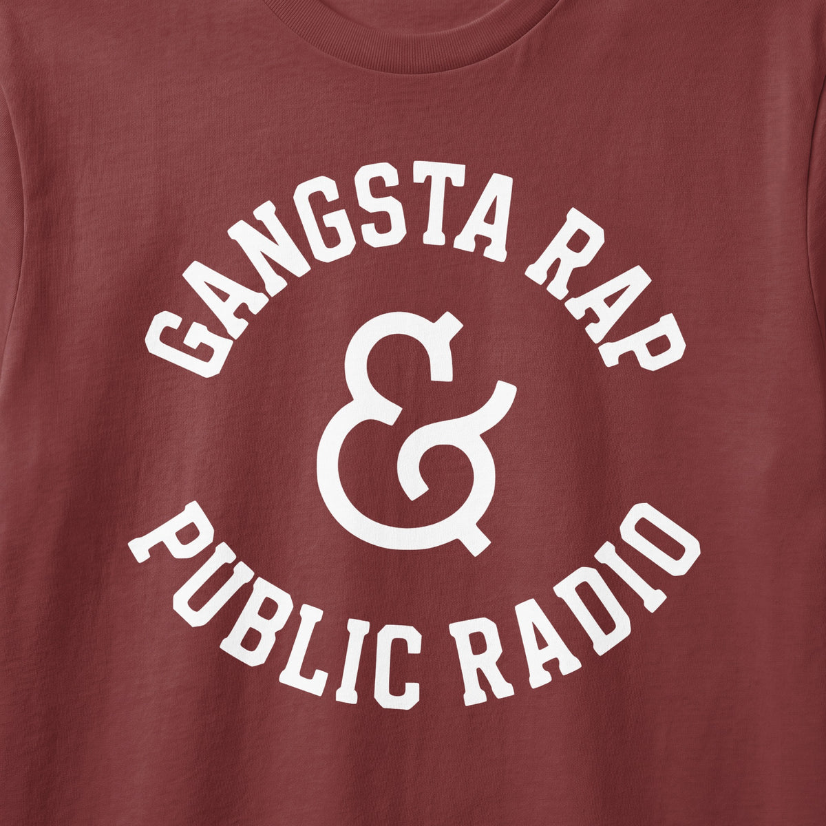 Brown t-shirt with white text "Gangsta Rap & Public Radio" in arched font.