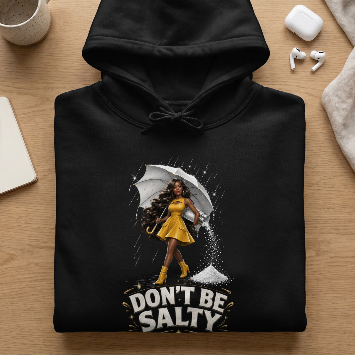 Black hoodie with "Don't Be Salty" graphic featuring a woman with an umbrella and salt shaker.
