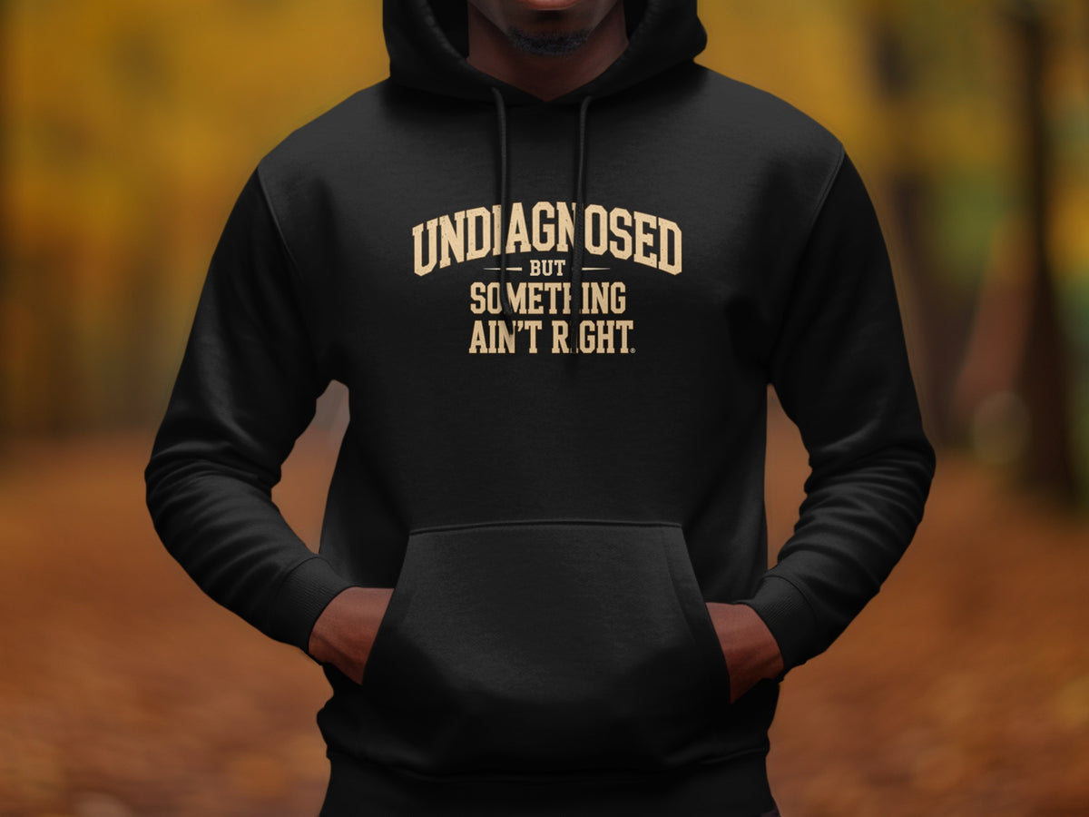 Black hoodie with "UNDIAGNOSED BUT SOMETHING AIN'T RIGHT." text.