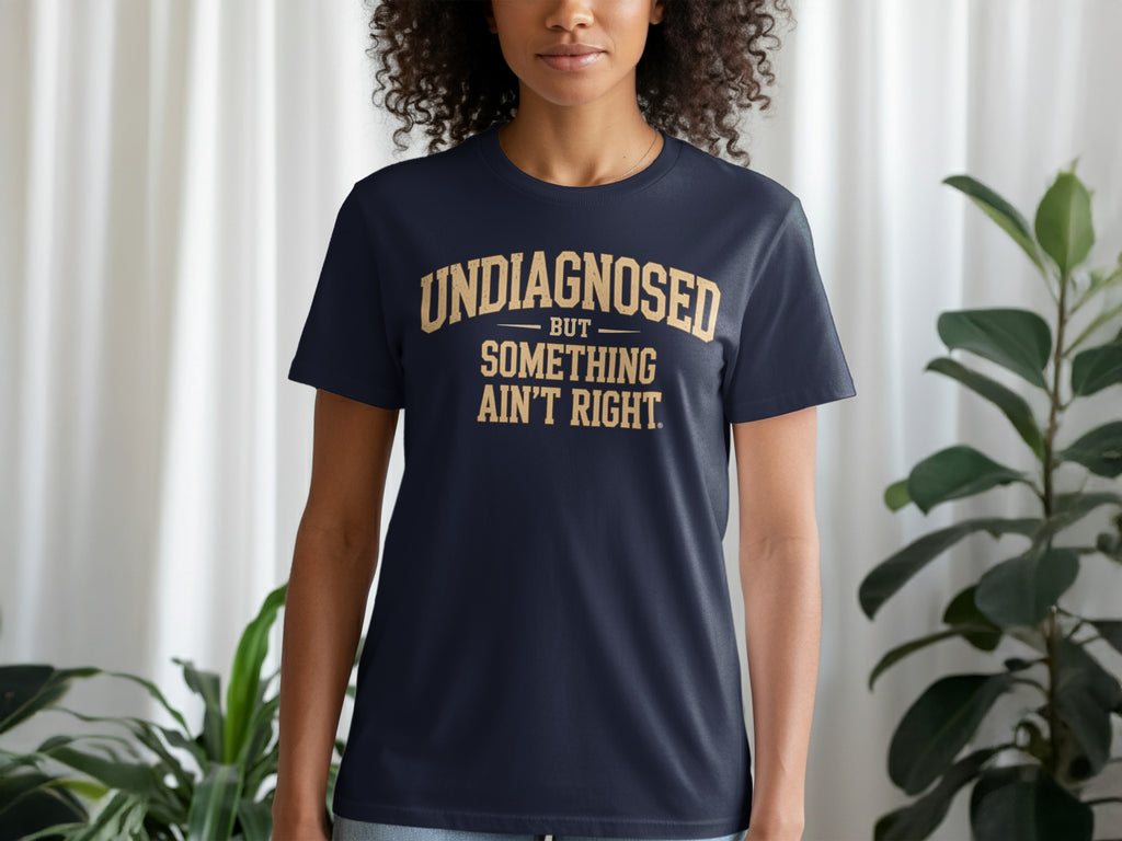 Navy t-shirt with gold text reading "UNDIAGNOSED BUT SOMETHING AIN'T RIGHT."