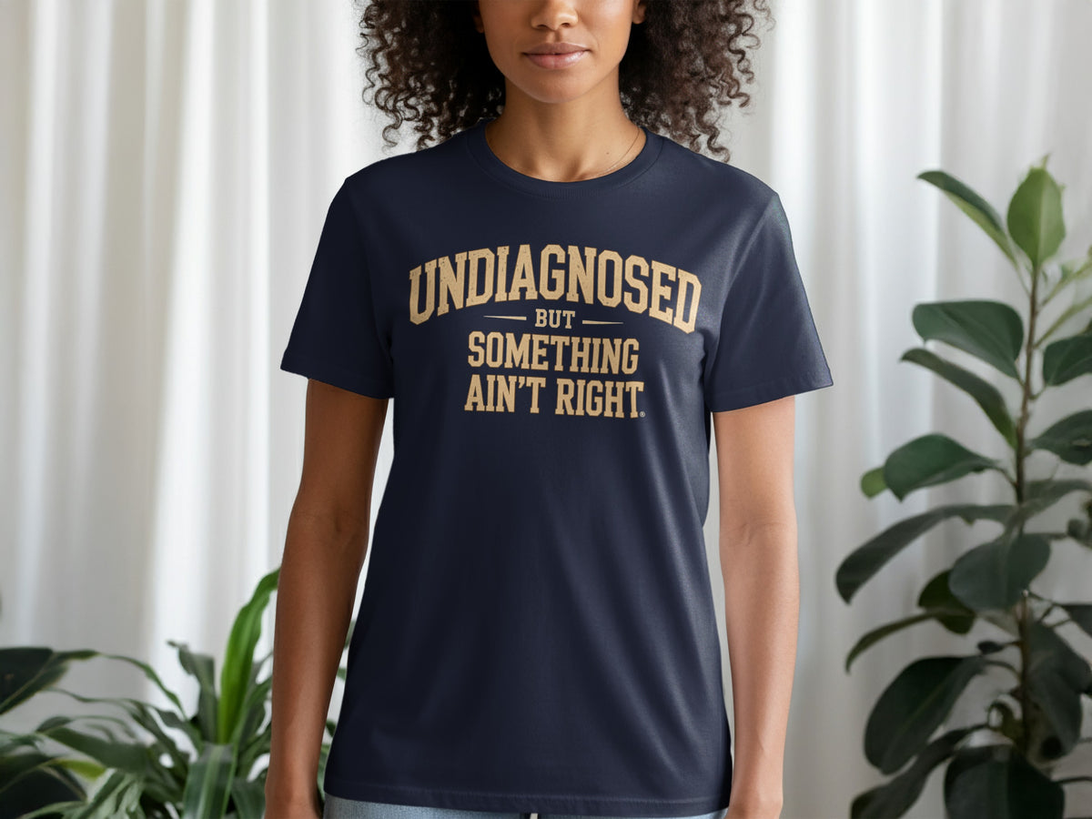 Navy t-shirt with gold text reading "UNDIAGNOSED BUT SOMETHING AIN'T RIGHT."