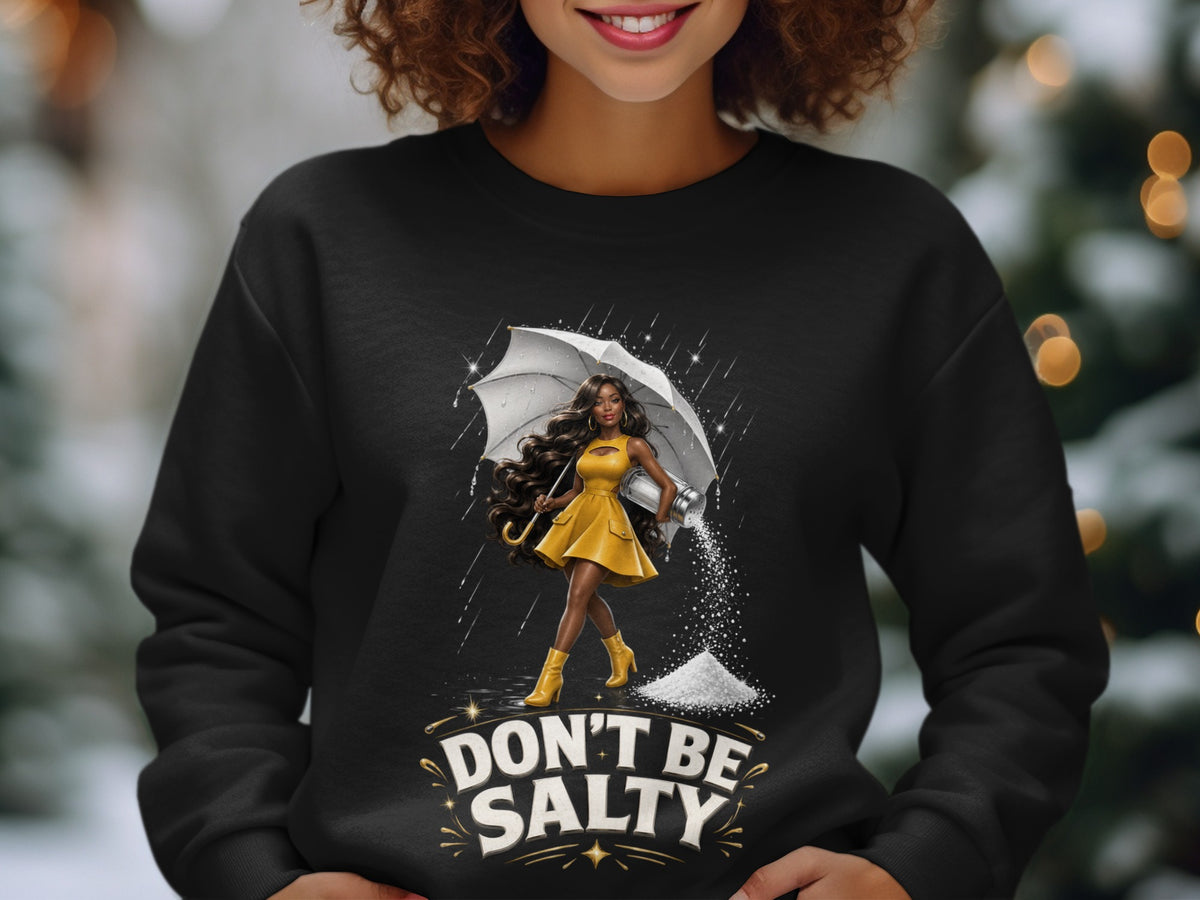 Black sweatshirt with graphic of woman holding umbrella, pouring salt, and text "DON'T BE SALTY".