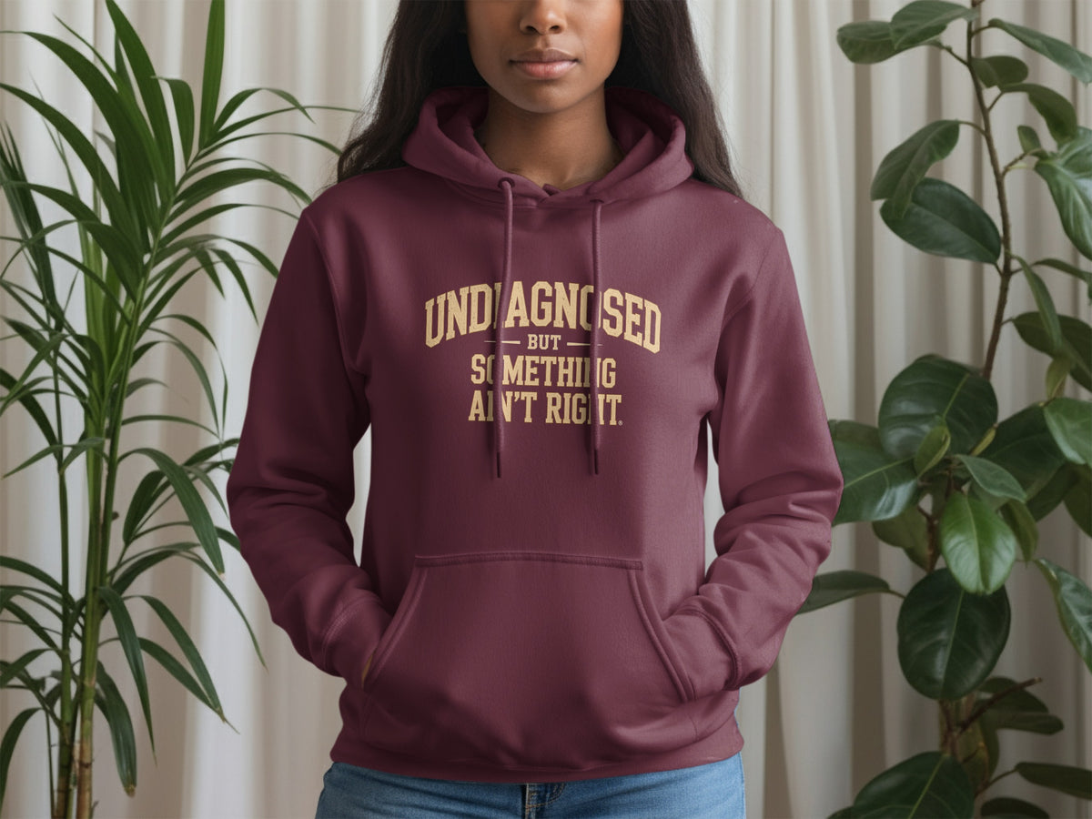 Maroon hoodie with gold text: "UNDIAGNOSED BUT SOMETHING AIN'T RIGHT."