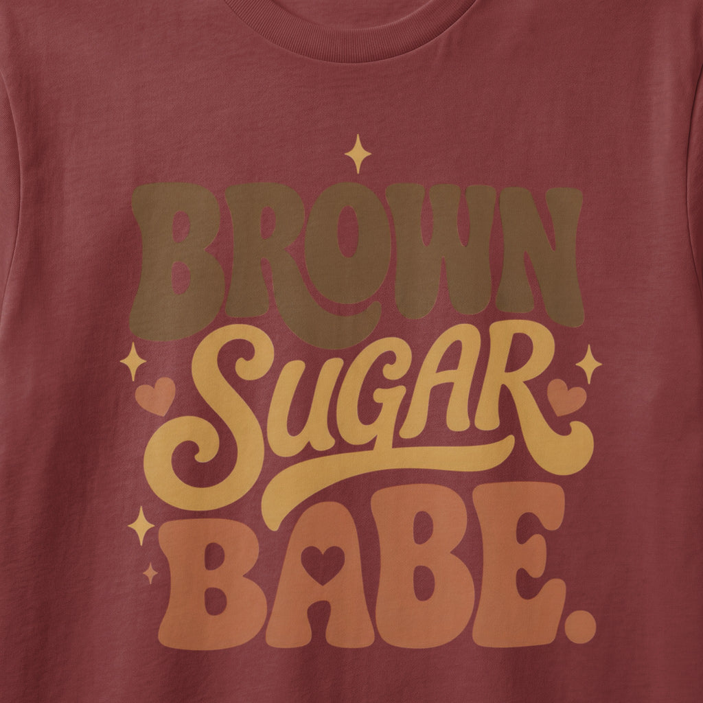 Brown Sugar Babe text with hearts and stars on a maroon shirt.