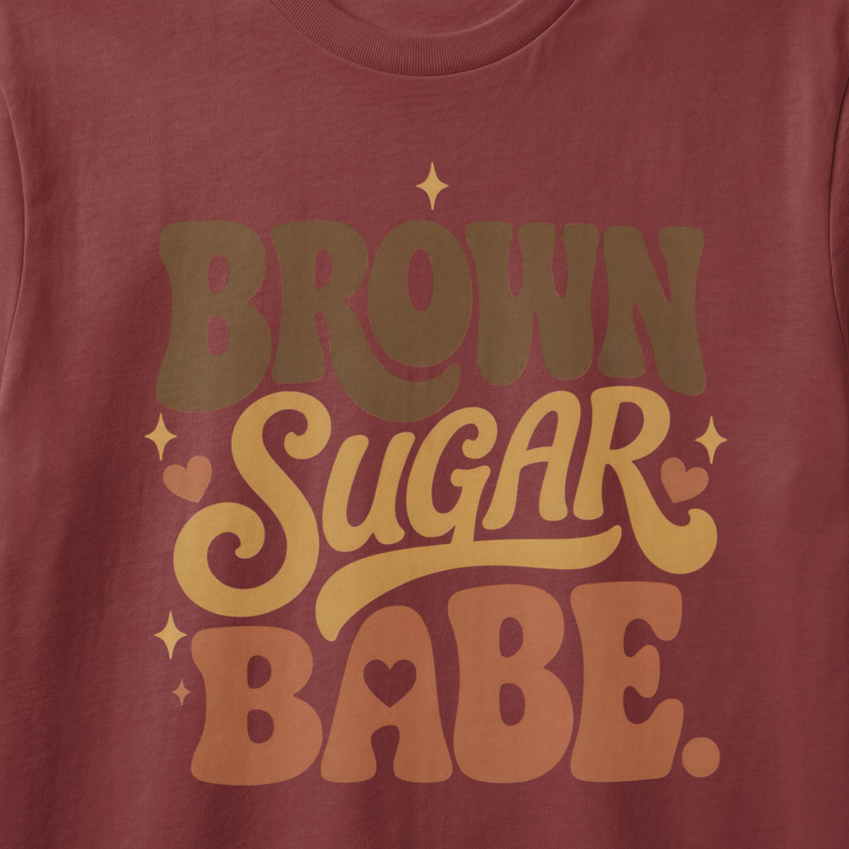 Brown Sugar Babe text with hearts and stars on a maroon shirt.