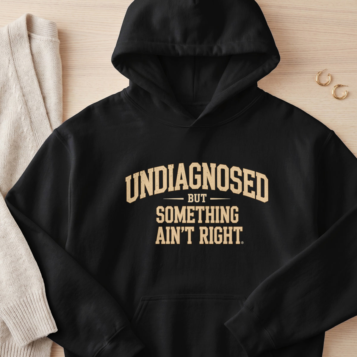 Black hoodie with "UNDIAGNOSED BUT SOMETHING AIN'T RIGHT" text.