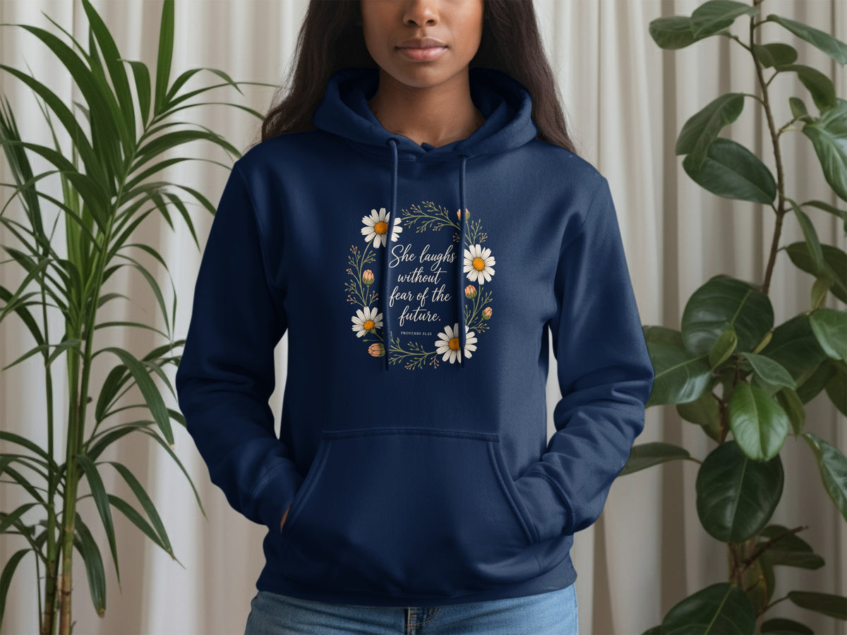 Navy blue hoodie with floral wreath design and text "She laughs without fear of the future."