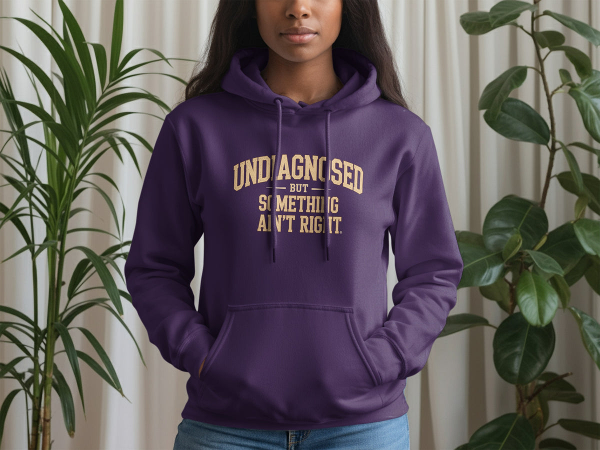 Purple hoodie with gold text "UNDIAGNOSED BUT SOMETHING AIN'T RIGHT."