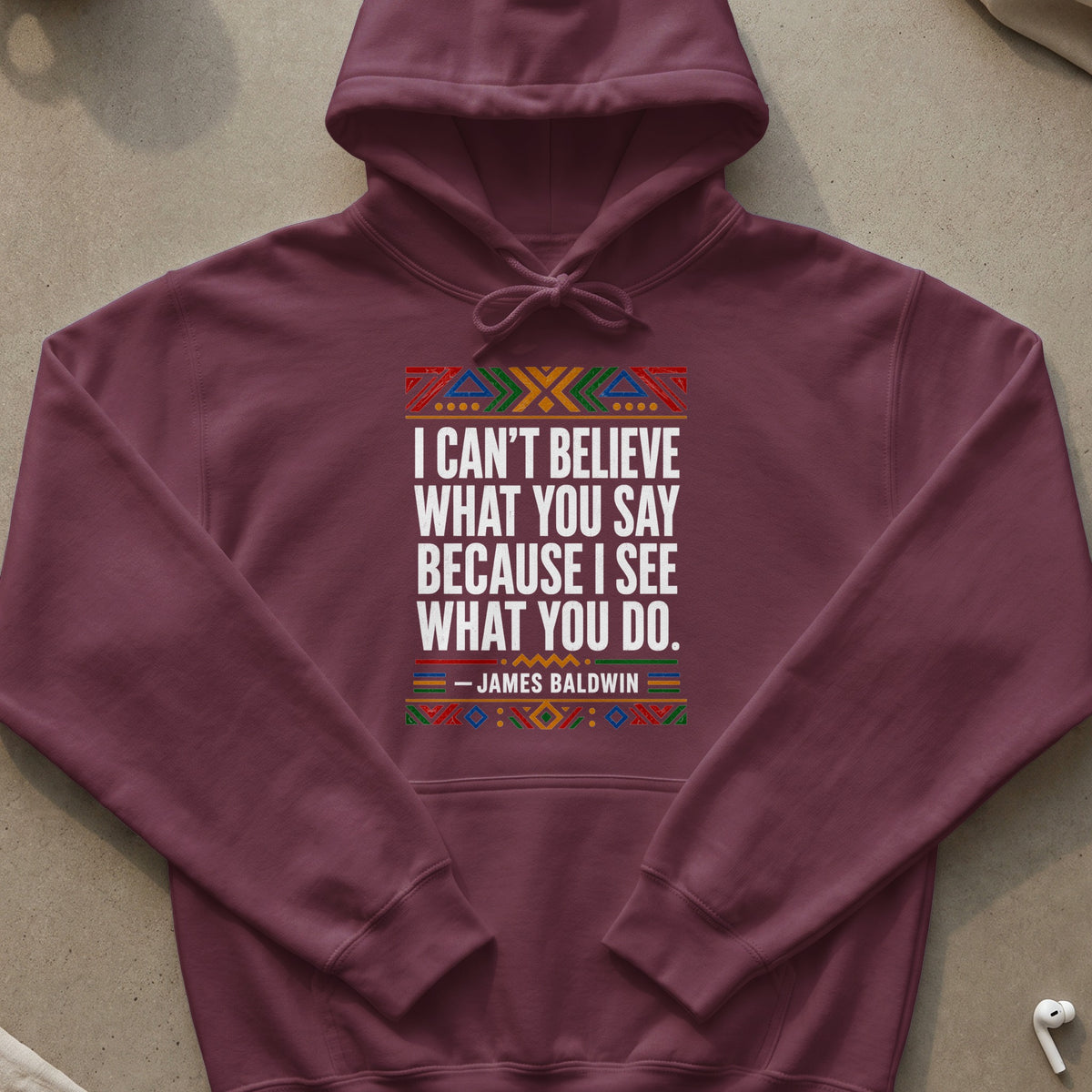 Maroon hoodie with James Baldwin quote, "I can't believe what you say because I see what you do."