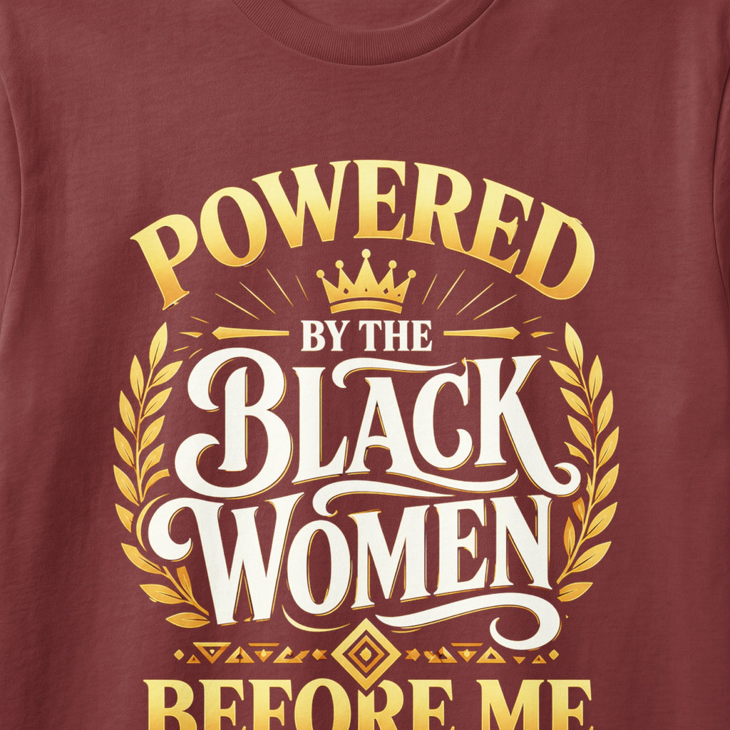 Maroon t-shirt with gold text "POWERED BY THE BLACK WOMEN BEFORE ME".