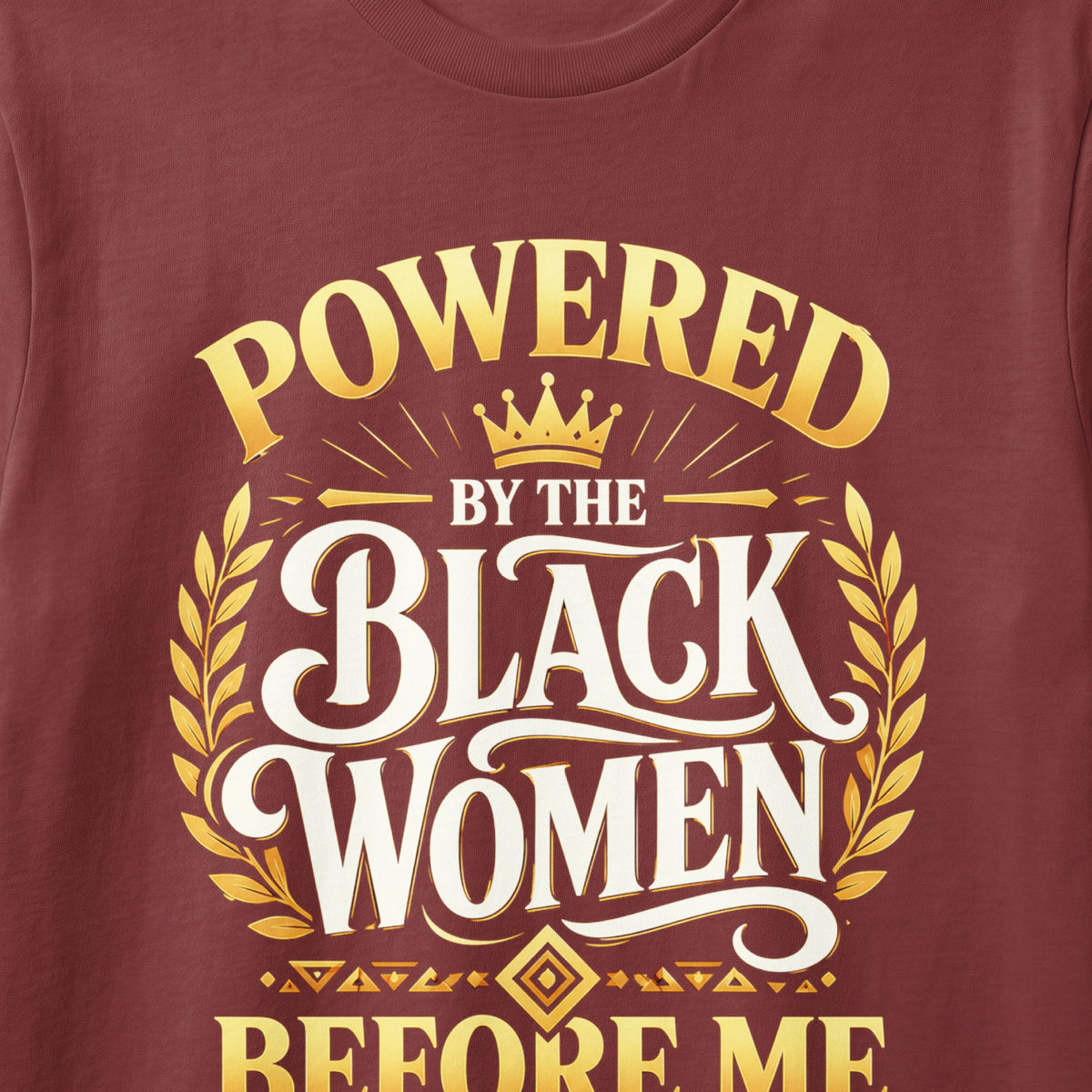 Maroon t-shirt with gold text "POWERED BY THE BLACK WOMEN BEFORE ME".