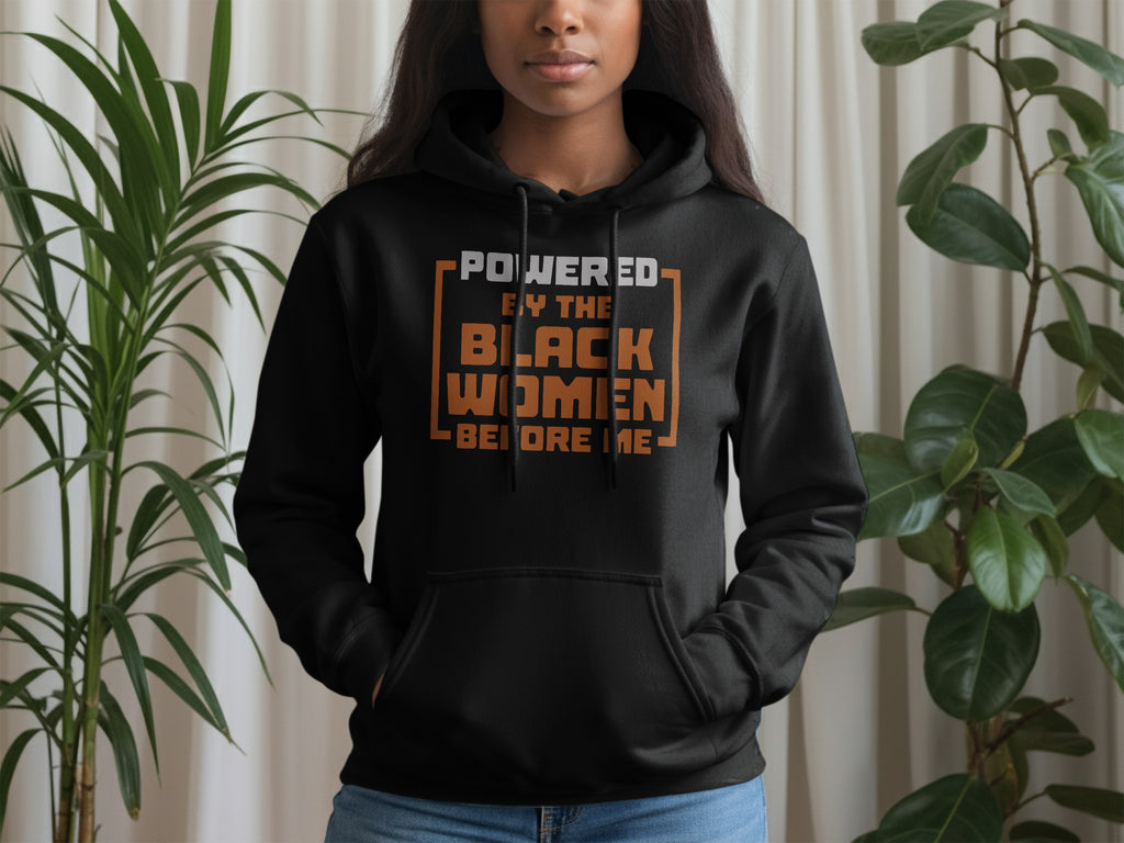 Black hoodie with "POWERED BY THE BLACK WOMEN BEFORE ME" text.