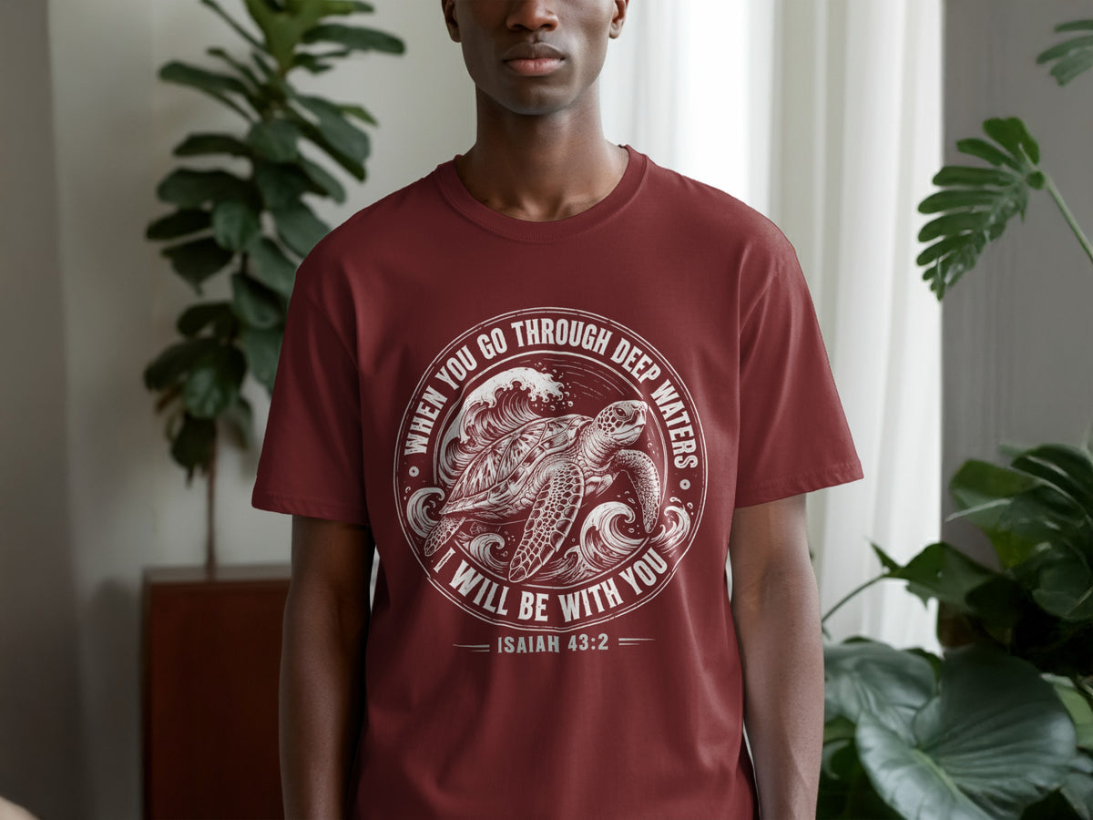 Maroon t-shirt with a white design of a sea turtle and waves with text Isaiah 43:2.