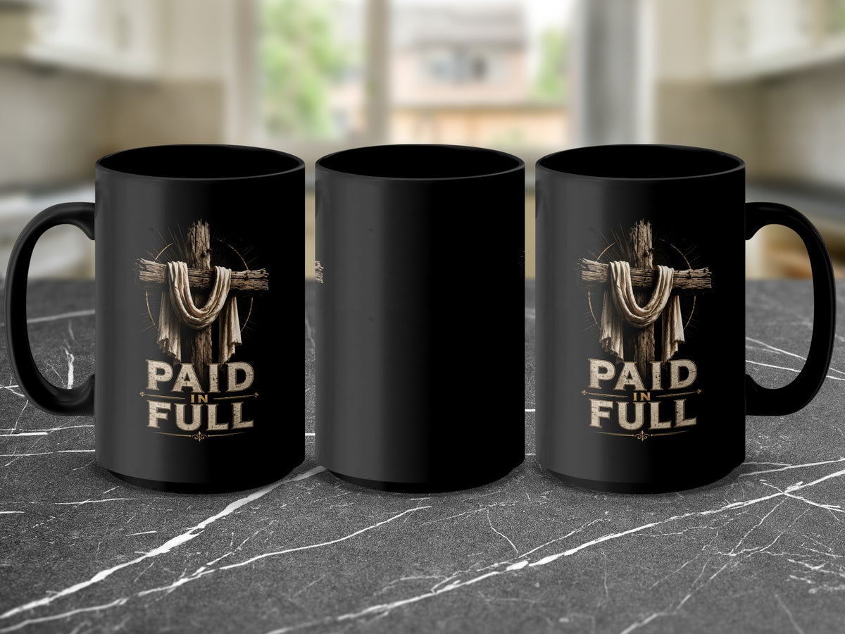 Black mug with a wooden cross, draped cloth, and "Paid in Full" text.