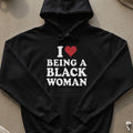 Black hoodie with white text reading "I ❤️ BEING A BLACK WOMAN".