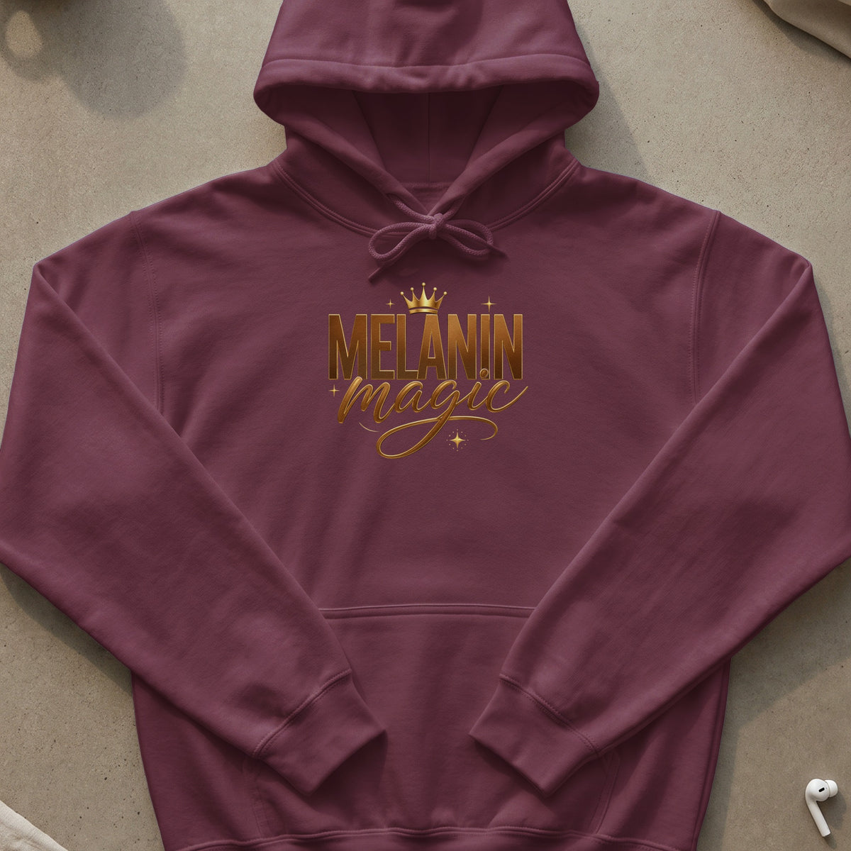 Maroon hooded sweatshirt with gold "MELANIN magic" text and crown graphic.