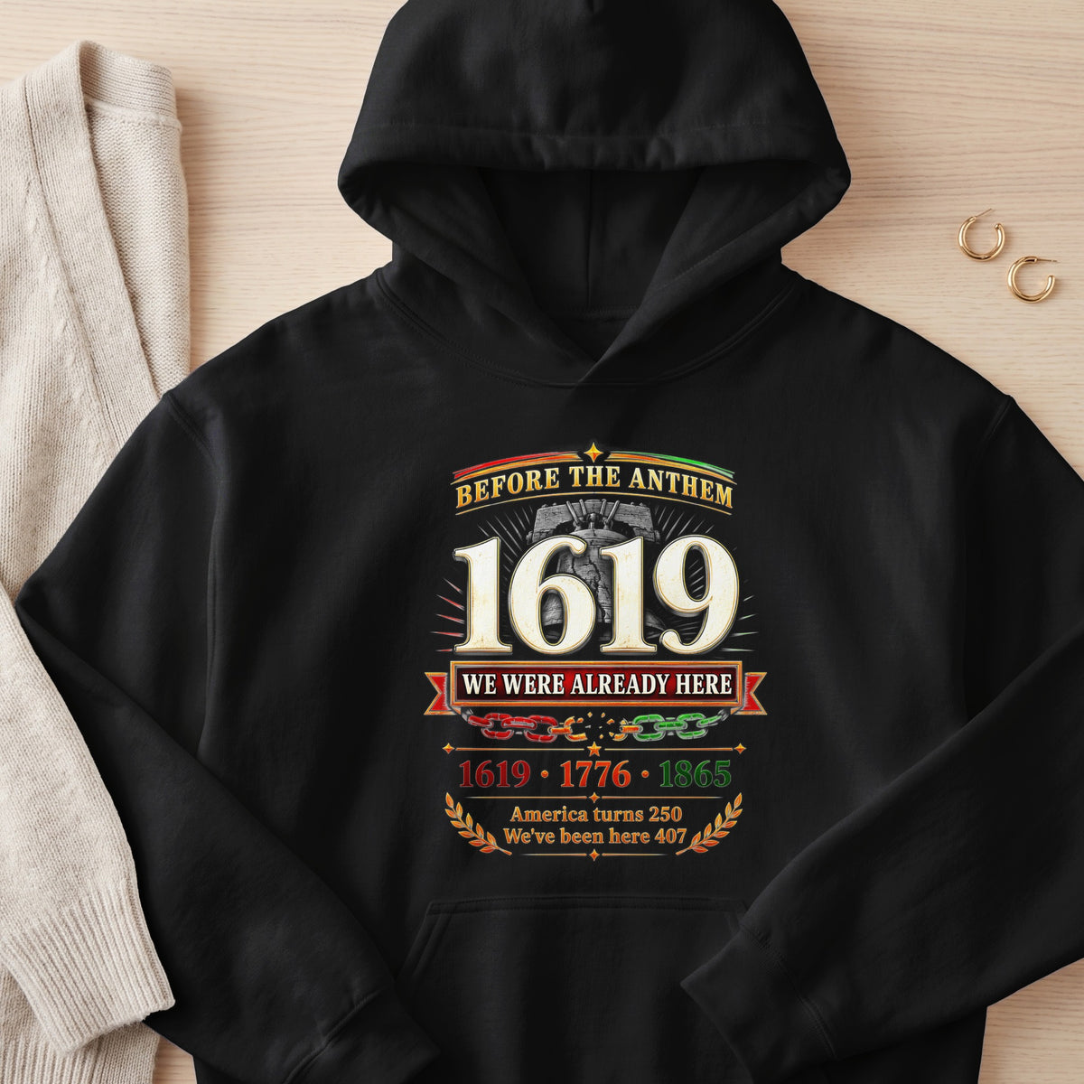 Black hoodie with "Before the Anthem 1619 We Were Already Here" text.