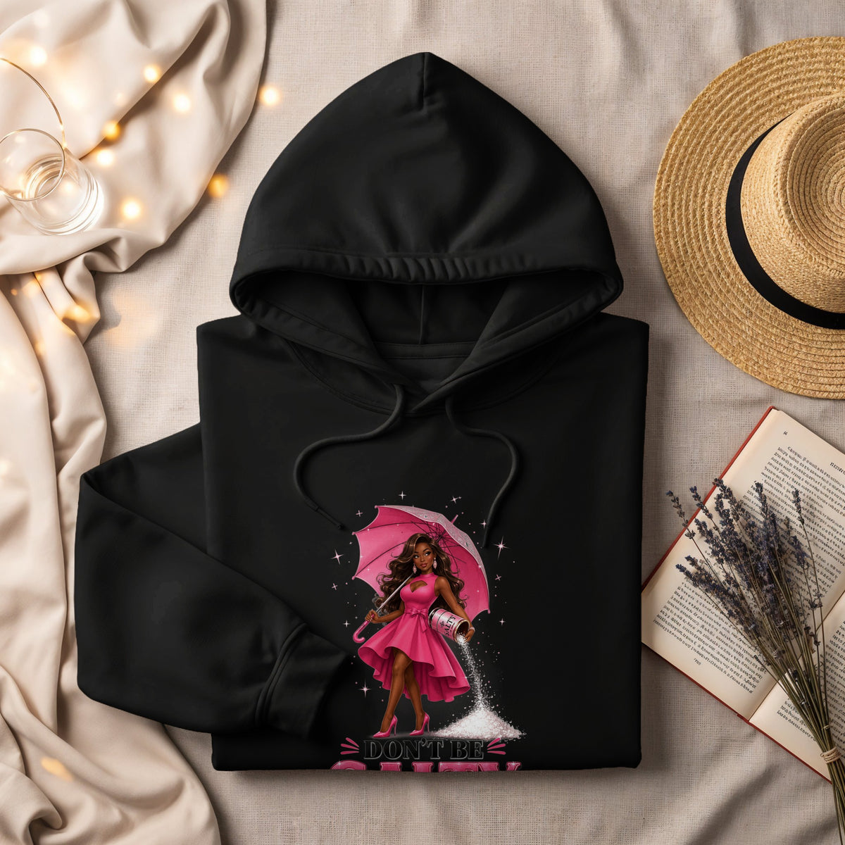 Black hoodie with graphic of woman holding umbrella and scattering salt, "Don't Be Salty" text.