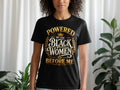 Black t-shirt with gold text: "POWERED BY THE BLACK WOMEN BEFORE ME".